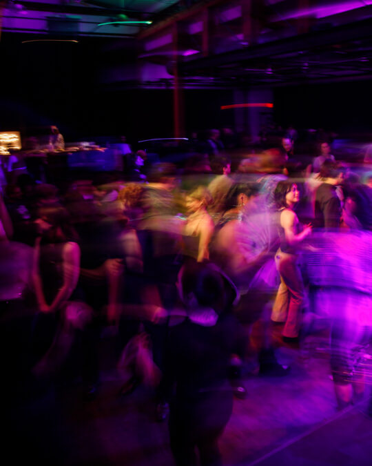 Artistically blurry full dance floor with trails of pink and purple light.