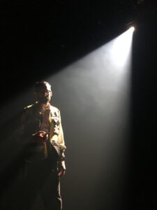A man in a reflective safety vest stands under a spotlight.