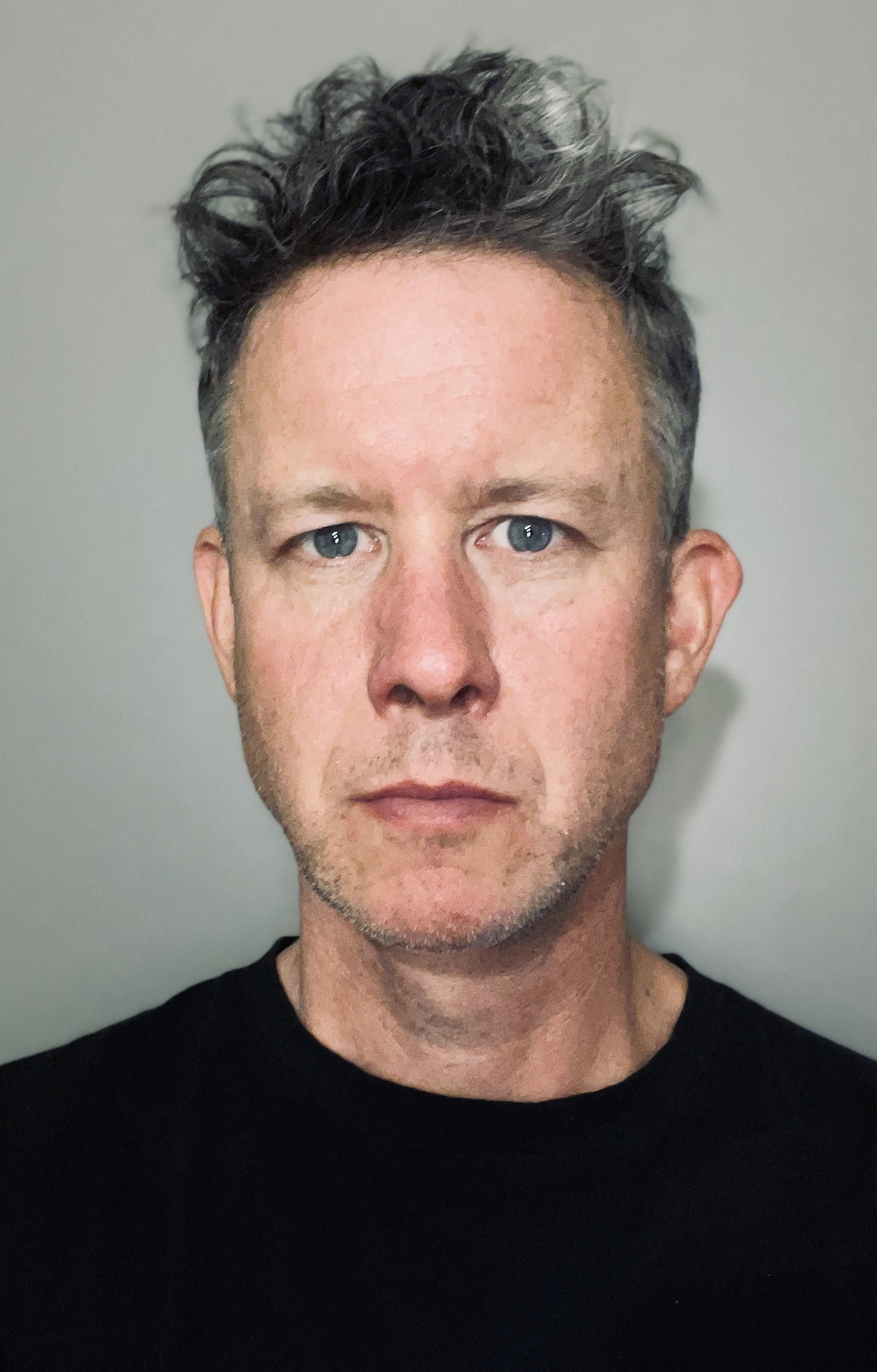 Portrait of a James Long, who has gray hair and is wearing a black shirt, looking at the camera